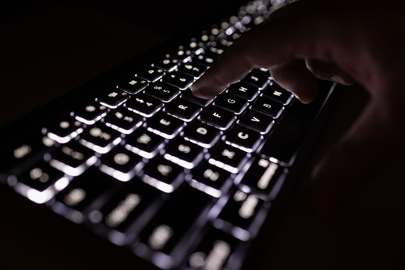 Hands typing on a keyboard while testing AI models at night