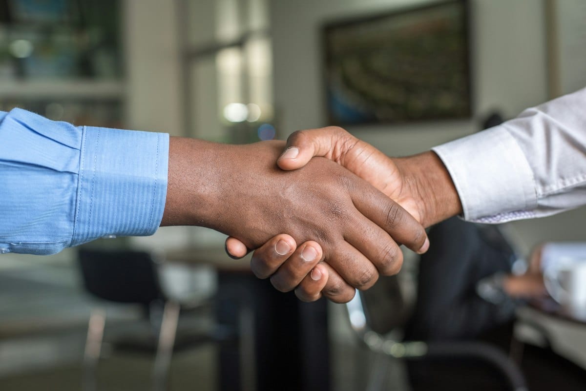 Real estate agent and client shaking hands over signed contract