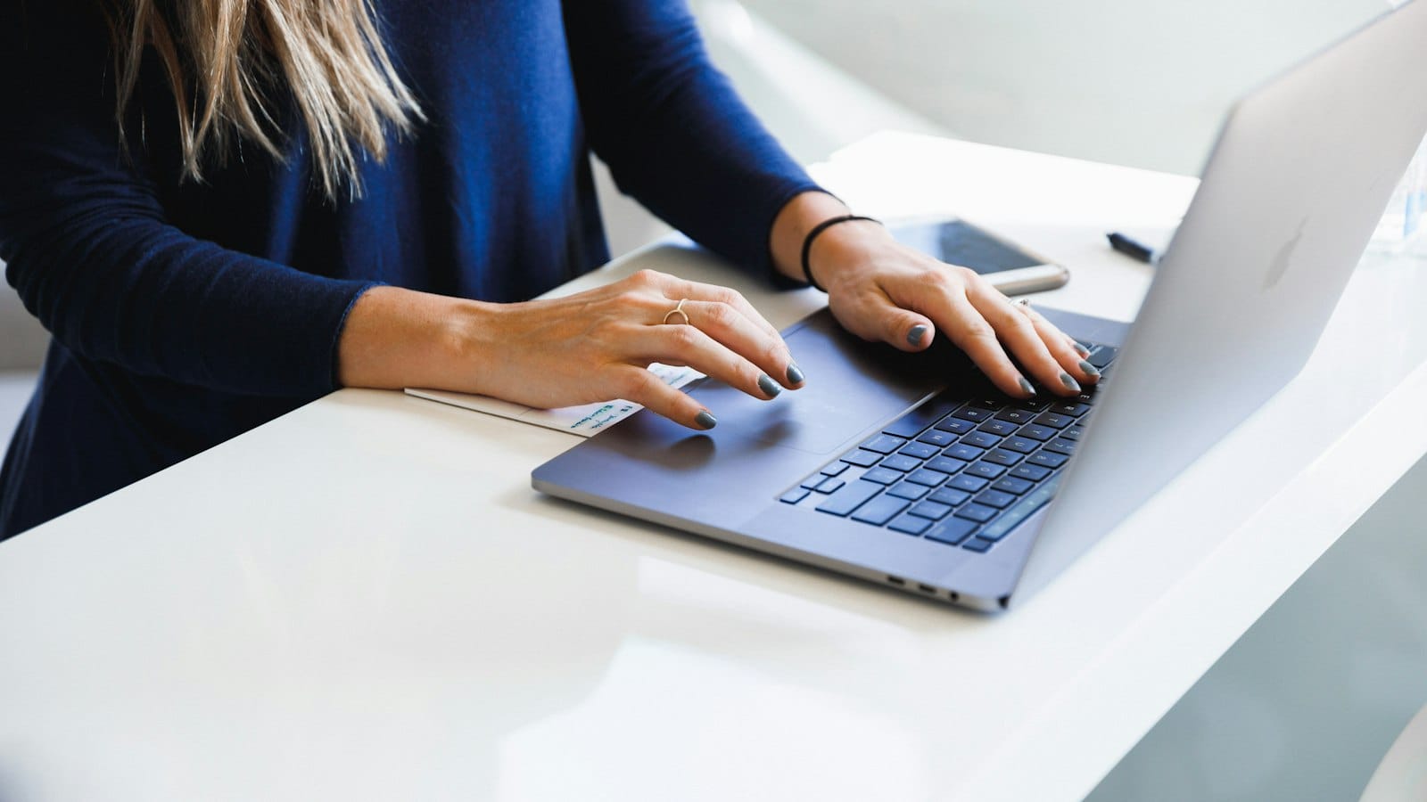 Woman typing on a laptop in a clean bright workspace
