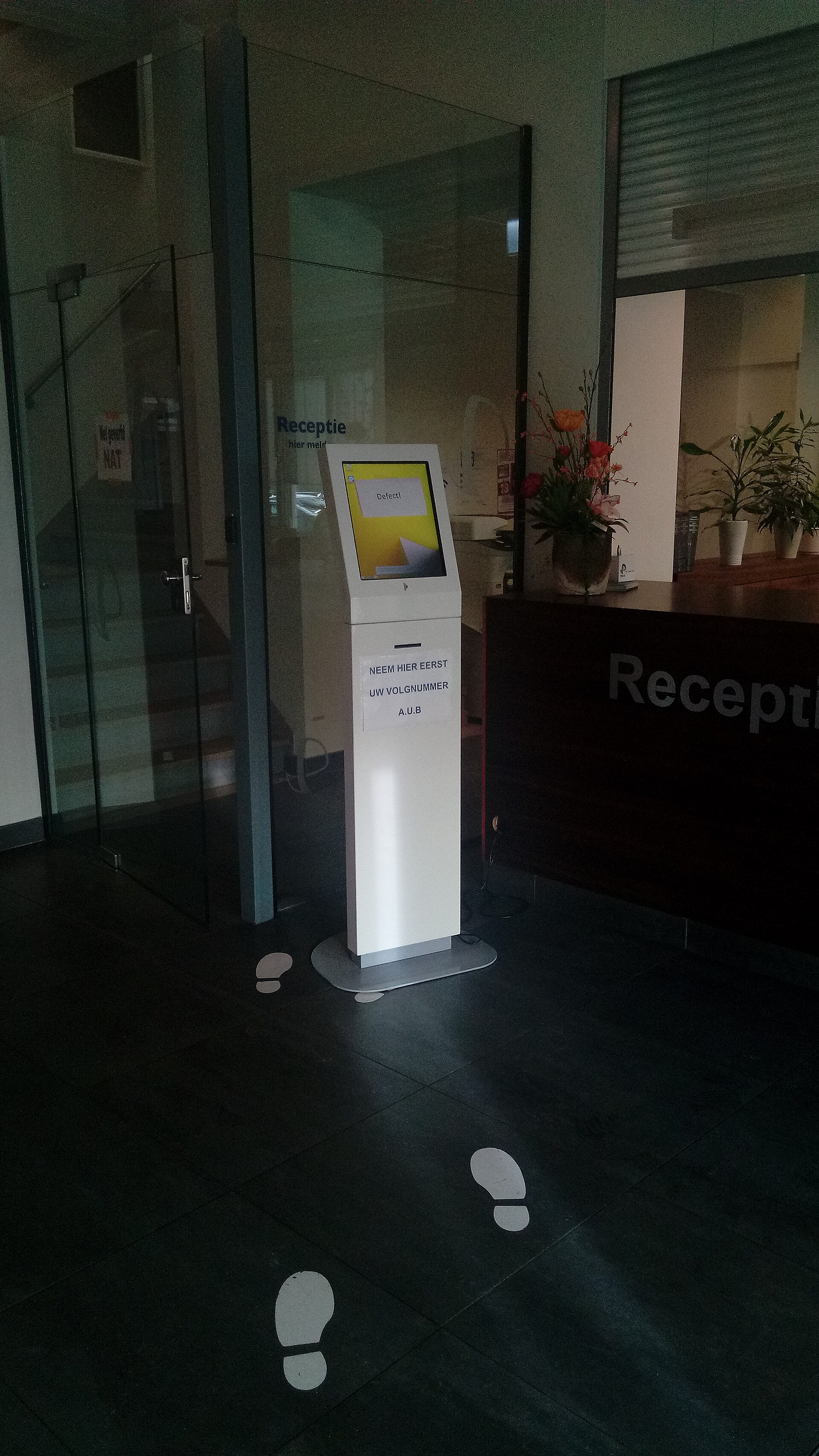 Customer using a self-service kiosk while waiting in a queue