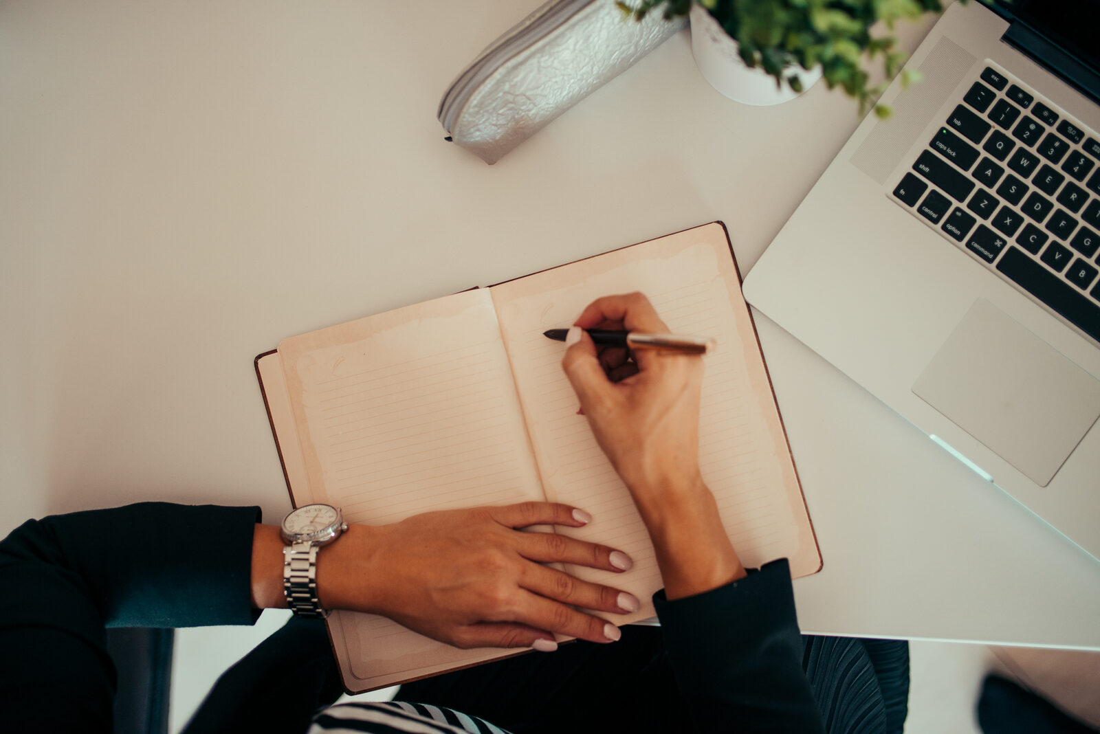 Marketer planning next year strategy in a notebook beside a laptop
