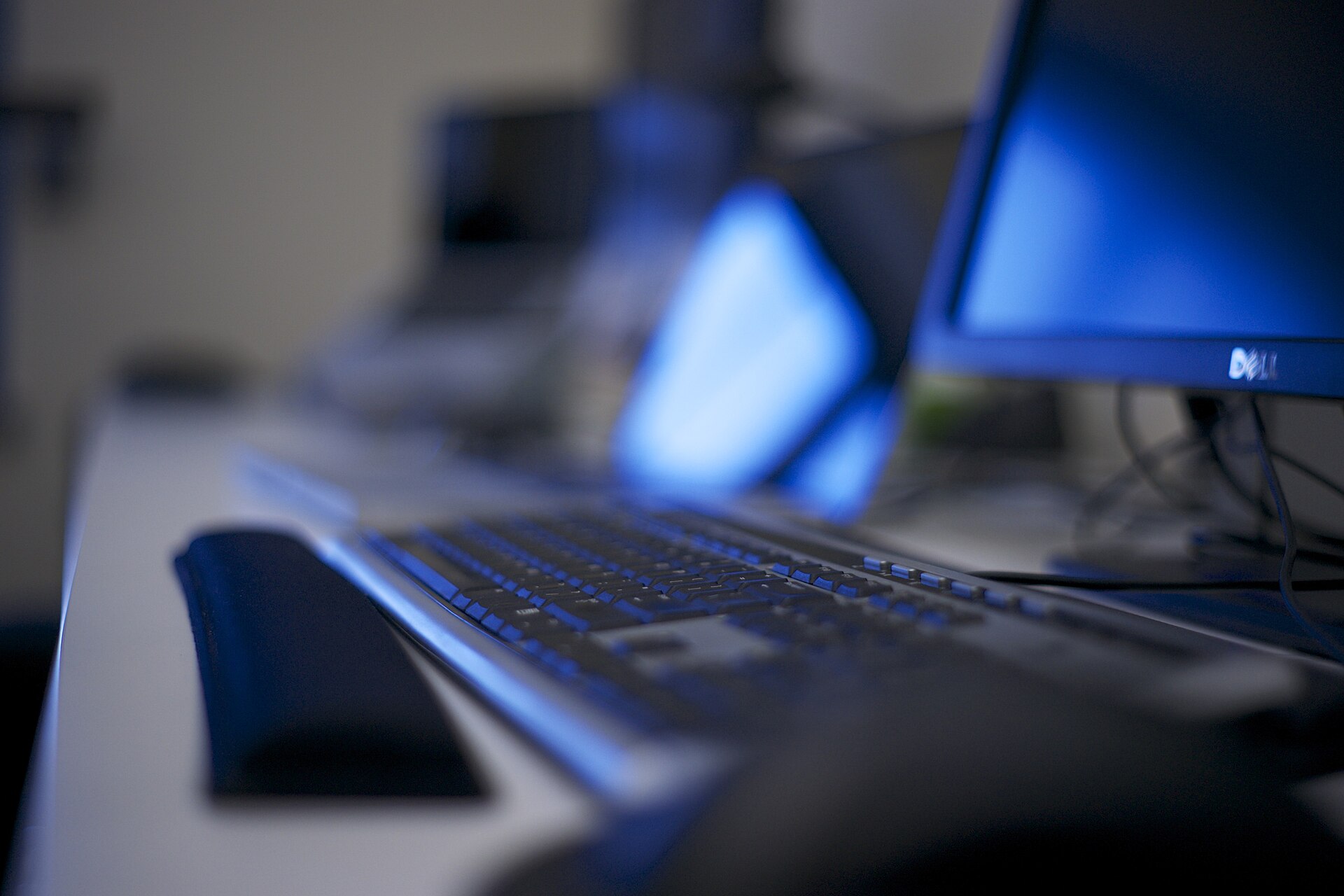 Photograph of several computers and laptops on desks in an office workspace